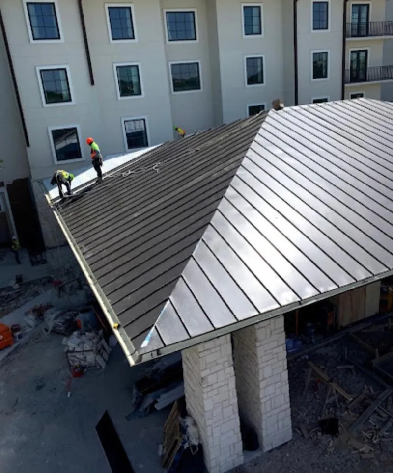 Crew installing standing seam metal roof panels on a commercial project in Larose
